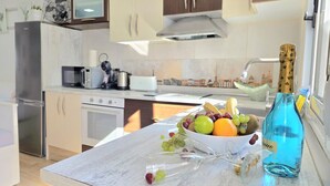 Una cocina moderna con armarios blancos, un refrigerador de acero inoxidable, un microondas, un tostador y un fregadero.