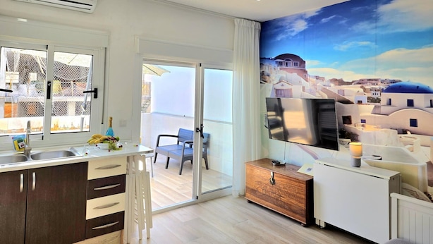 Una cocina moderna con un ventanal grande, un balcón y un mural de un pueblo costero.