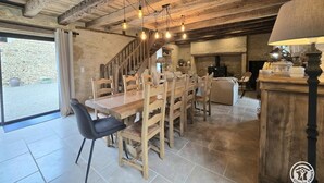 A rustic dining area with a wooden table and chairs, a staircase, and a fireplace. - Stone house in Périgord, sleeps 10, authentic charm (La Chapelle-Aubareil)
