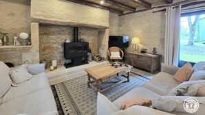 A rustic living room with a stone fireplace, a television, and a sofa. - Stone house in Périgord, sleeps 10, authentic charm (La Chapelle-Aubareil)
