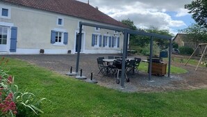 Una casa con patio coperto, arredi da esterno e altalena.