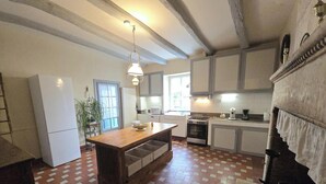 Una cucina con isola centrale, mobili bianchi, un fornello e un lampadario.