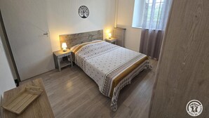 Una camera da letto con un letto di legno, lampade sui comodini, un termosifone e una finestra con tende.