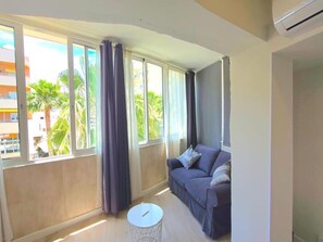 A modern living room with a curved sofa, a small round table, and large windows with curtains. - Modern studio in central Torremolinos (Torremolinos)