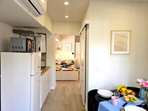 A compact kitchen with a refrigerator, microwave, and a small oven. A dining area with a table set for two, featuring a fruit bowl, plates, and a vase of flowers. - Modern studio in central Torremolinos (Torremolinos)
