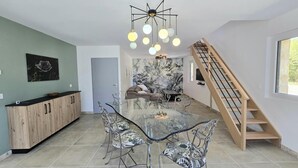 Una cucina moderna con un tavolo da pranzo in vetro, mobili a parete in legno e un originale lampadario.