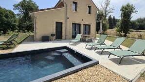 Una casa a due piani con piscina, area relax all'aperto e giardino.