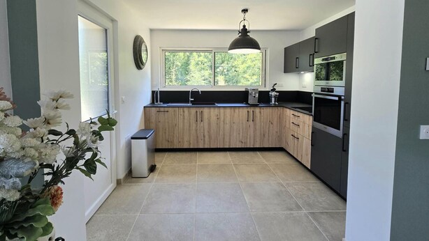 Una cucina moderna con mobili in legno, forno integrato e una finestra che lascia entrare luce naturale.