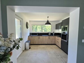 Eine moderne Küche mit Holzschränken, einem Einbauofen und einem Fenster, das für natürliches Licht sorgt.