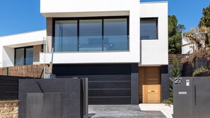 A modern two-story house with a large glass window and a black garage door.