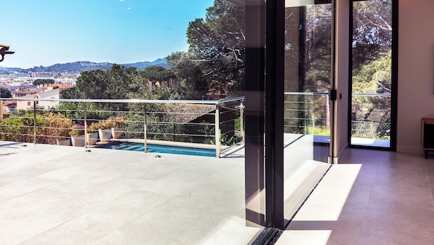 A modern balcony with a pool, large glass doors, and a city view.