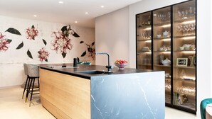 A modern kitchen with a marble island, a sink, and a backsplash with floral wallpaper.