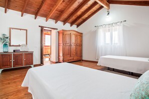 Ein Schlafzimmer mit Holzboden, einem Bett, einem Kleiderschrank, einem Spiegel und einem Fenster mit Vorhängen.
