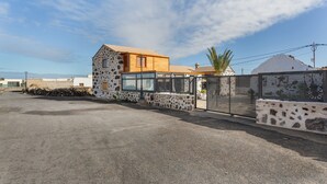 Een modern huis met een stenen gevel, een houten bovenverdieping en een hekwerk.