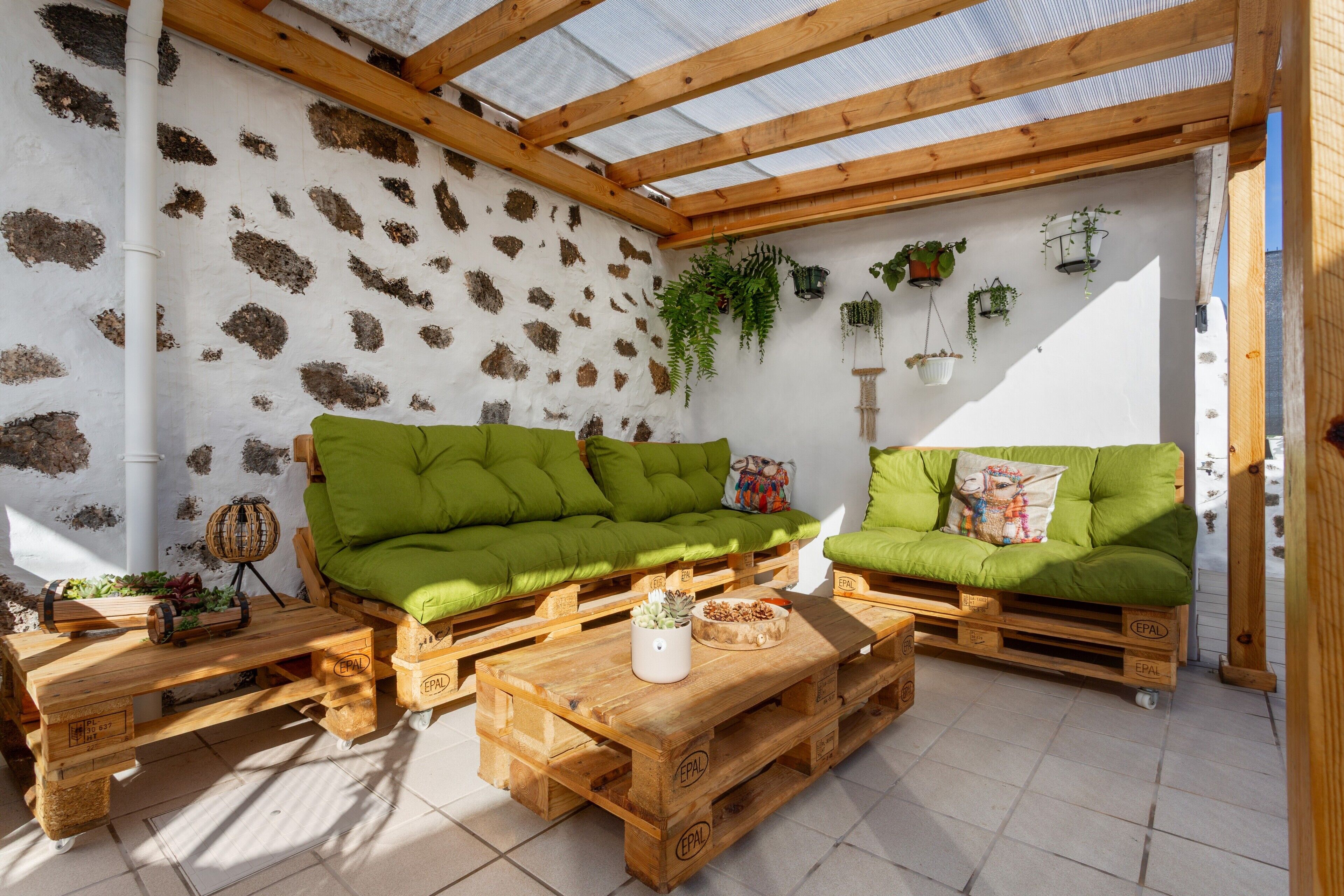 Un porche cubierto con muebles de madera y plantas en macetas.