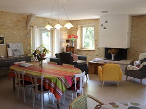 A spacious living area with a dining table, chairs, sofas, and a fireplace.