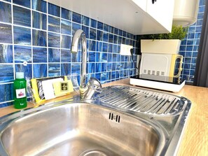 A kitchen with a stainless steel sink, blue tiled backsplash, a microwave, and a green bottle of dish soap. - Elegant Central Studio in Torremolinos (Torremolinos)