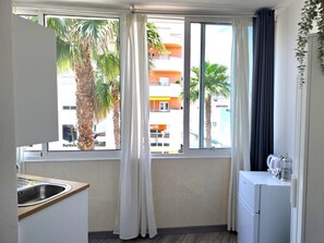 A compact kitchen with a sink, a small refrigerator, and a window with curtains. - Elegant Central Studio in Torremolinos (Torremolinos)