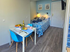 A small, compact room with a bed, a dining table with chairs, and a kitchenette area. - Elegant Central Studio in Torremolinos (Torremolinos)