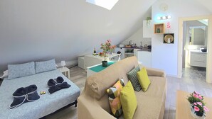 Une chambre de style loft moderne, dotée d’une lucarne, d’un canapé, d’un lit et d’une kitchenette.