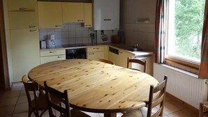 Une cuisine avec des meubles de rangement jaunes, une table à manger en bois et une fenêtre avec des rideaux.