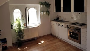 Een keuken met witte kasten, een fornuis en een raam met twee planten.