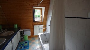 Un bagno piccolo e compatto con soffitto in legno, una finestra, una vasca e un lavandino.