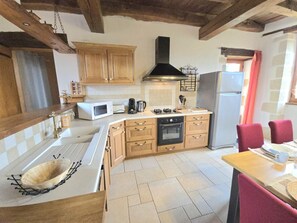 A kitchen with wooden cabinets, a gas stove, a microwave, and a refrigerator. - Charming house in Hautefort with private pool, pets allowed (Hautefort)