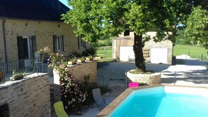 Ein Swimmingpool mit Liegestühlen, einem Baum und einem Gebäude mit Fensterläden.