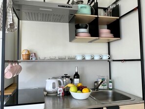 A compact kitchen with a coffee machine, kettle, and a bowl of fruit on the counter. - Modern Studio Benalmádena with Views (Marbella)