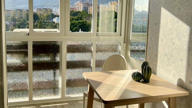 Una habitación con un gran ventanal que ofrece vistas a un paisaje urbano y montañas.