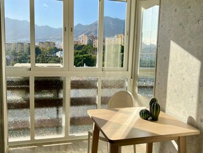 A room with a large window offering a view of a cityscape and mountains. - Modern Studio Benalmádena with Views (Marbella)