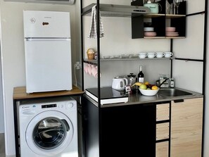 A compact kitchenette with a white refrigerator, a washing machine, and a sink area with various kitchen items. - Modern Studio Benalmádena with Views (Marbella)
