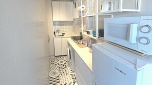Une cuisine de taille réduite avec des meubles blancs, un four à micro-ondes et un carrelage décoratif.