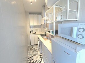 A compact kitchen with white cabinets, a microwave, and a patterned floor. - Elegant urban retreat in Torremolinos with panoramic terraces (Torremolinos)