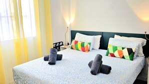 Une chambre d’hôtel avec un lit, des oreillers, une table de chevet et une lampe.