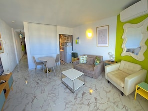 A living room with a sofa, a coffee table, and a dining area with chairs and a table. - Elegant urban retreat in Torremolinos with panoramic terraces (Torremolinos)