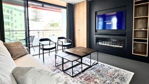 Een moderne woonkamer met een bank, een salontafel, een televisie en een open haard.