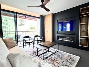 A modern living room with a sofa, a coffee table, a TV, and a fireplace.