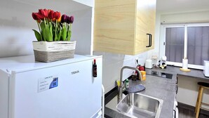 A modern kitchen with a white refrigerator, a sink, and a wooden cabinet above the countertop. - Elegant 3-Bedroom Apartment in Torremolinos - Wifi and Air Conditioning (Torremolinos)
