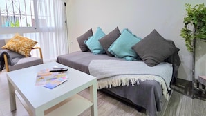 A modern living room with a sofa, a coffee table, and a potted plant. - Elegant 3-Bedroom Apartment in Torremolinos - Wifi and Air Conditioning (Torremolinos)
