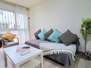 A modern living room with a sofa, a coffee table, and a potted plant. - Elegant 3-Bedroom Apartment in Torremolinos - Wifi and Air Conditioning (Torremolinos)