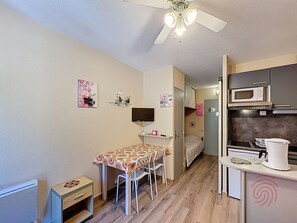 A compact room with a kitchenette, a dining area with a table and chairs, a ceiling fan, and a bed. - Studio in Lamalou-les-Bains near center with Wifi (Lamalou-les-Bains)