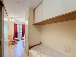 Une chambre avec un lit superposé, une petite table avec des chaises et une fenêtre avec des rideaux.