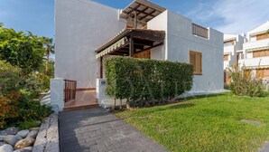 Un immeuble résidentiel moderne à deux étages, doté d’un chemin pavé menant à l’entrée et entouré de verdure.