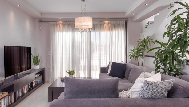 Un salon moderne avec un grand canapé gris, un téléviseur à écran plat et une bibliothèque.
