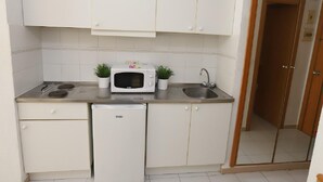A compact kitchen with white cabinets, a microwave, a sink, and a small refrigerator. - Cozy Studio with Terrace, Pools, AC, Near Beach, Sleeps 4 (Salou)