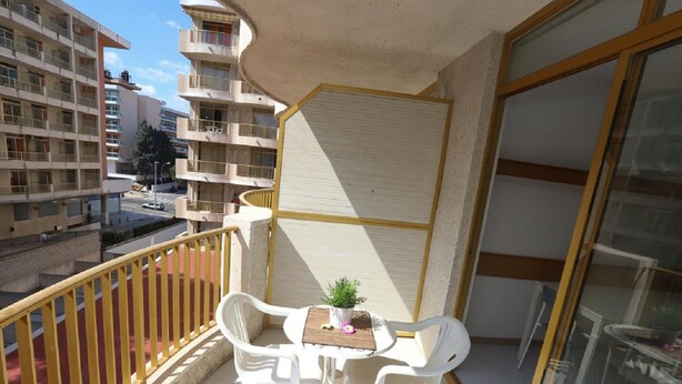 A balcony with two white plastic chairs, a small table, and a potted plant. - Cozy Studio with Terrace, Pools, AC, Near Beach, Sleeps 4 (Salou)