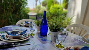 Una mesa puesta para una comida, con platos, cuencos, vasos y una botella azul.