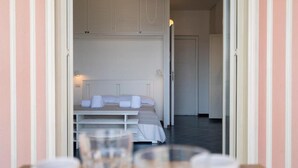 A hotel room with a neatly made bed, a bedside table with a glass, and a door leading to another room. - Naxos Seaside Escape: Terrace (Giardini Naxos)
